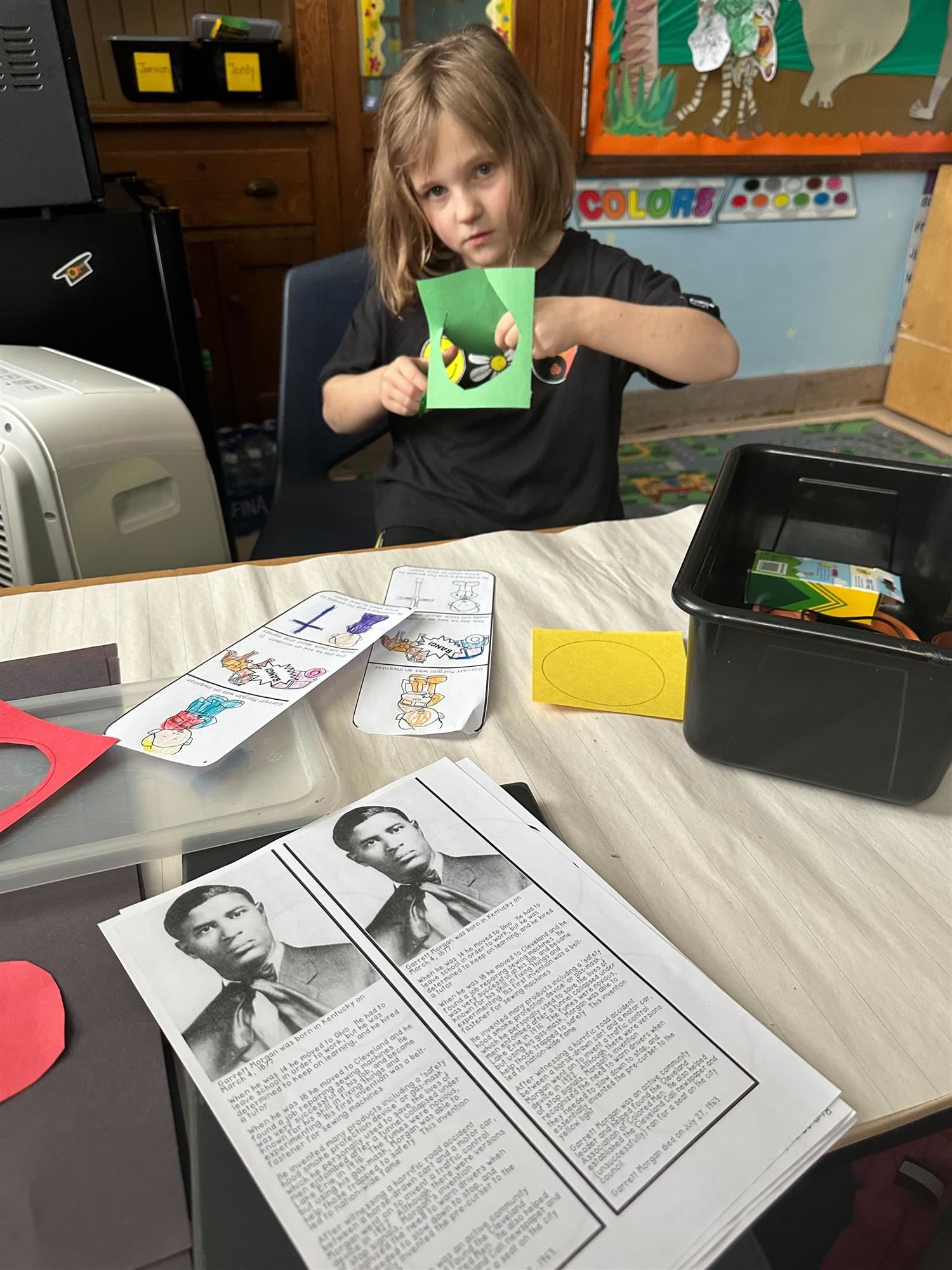 Photo of student cutting out a circle from a piece of green construction paper to create a paper traffic light. 